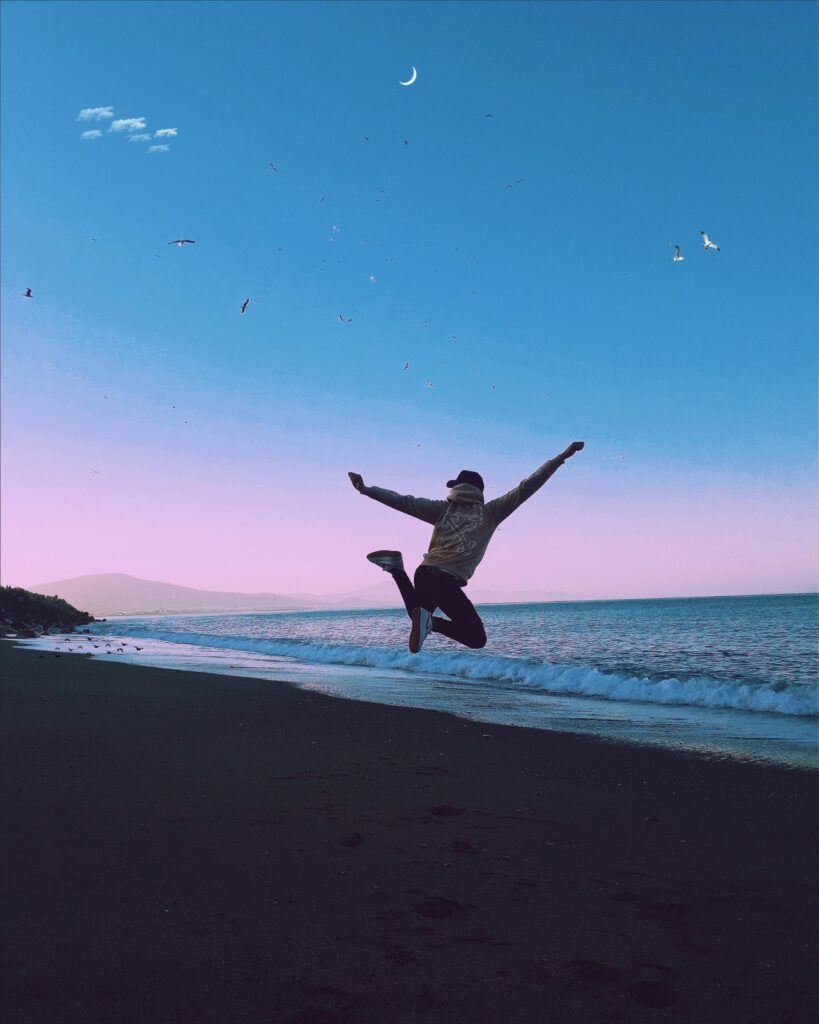pexels-photo-2041832-2041832 A man jumping on a beach under a crescent moon, symbolizing freedom and joy.